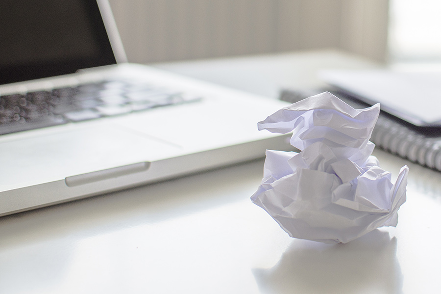 Laptop and crumpled paper representing error